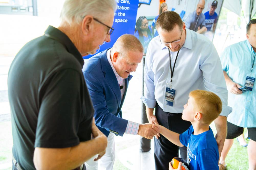 Brian Kelly shaking hands with a child at the Jamie Hosford Football Center dedication.